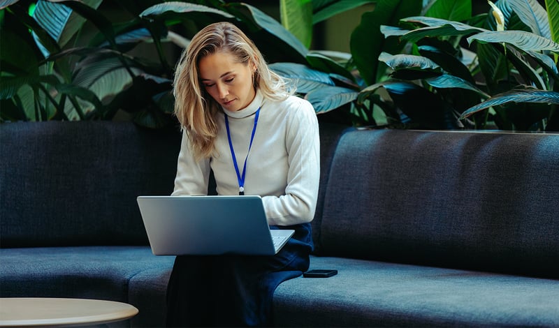 Kvindelig leder arbejder på bærbar computer, symboliserer APV og trivselsmåling for medarbejderengagement.